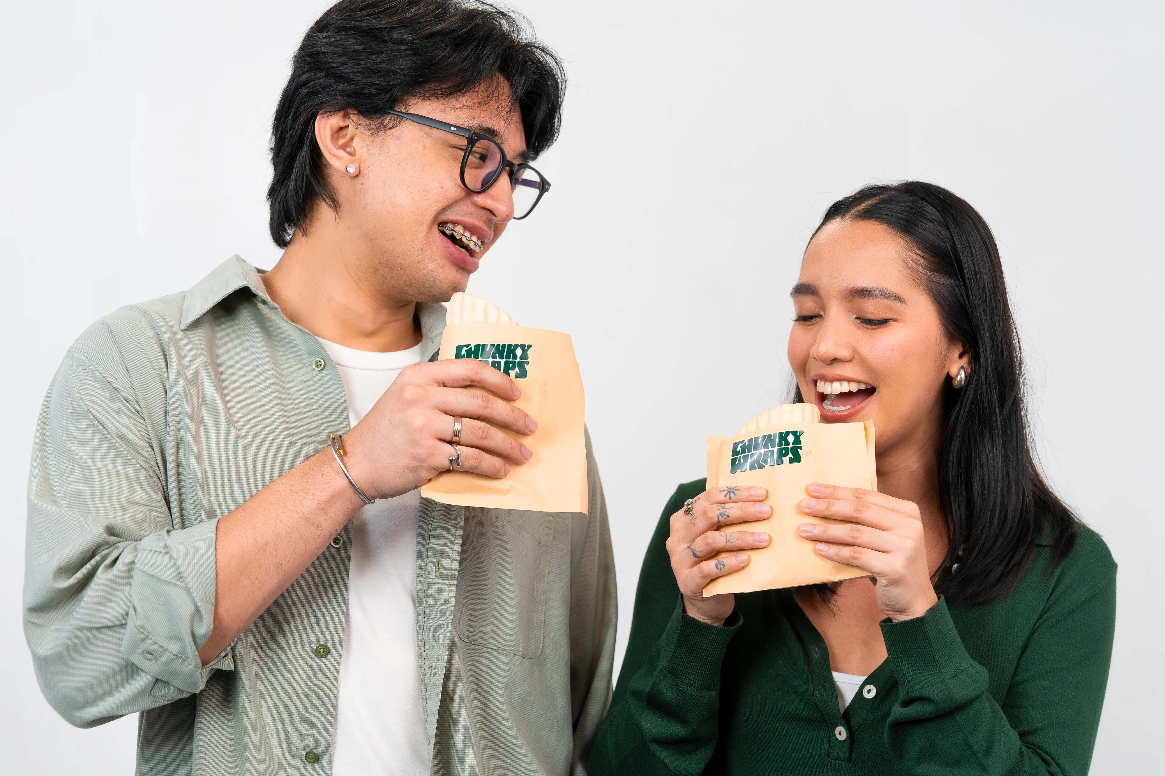 Two friends laughing while biting into Chunky Wraps